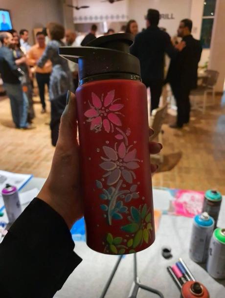 Garrafa metálica pintada à mão com flores durante evento