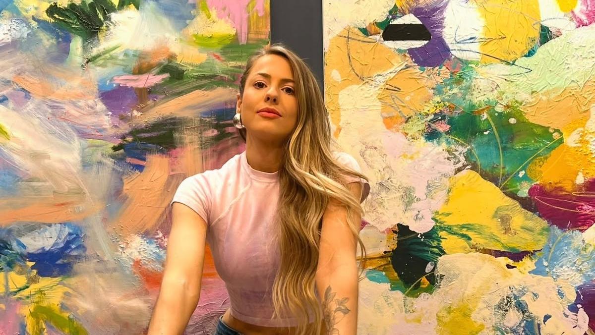 Raíssa Schröeder em frente a duas de suas pinturas